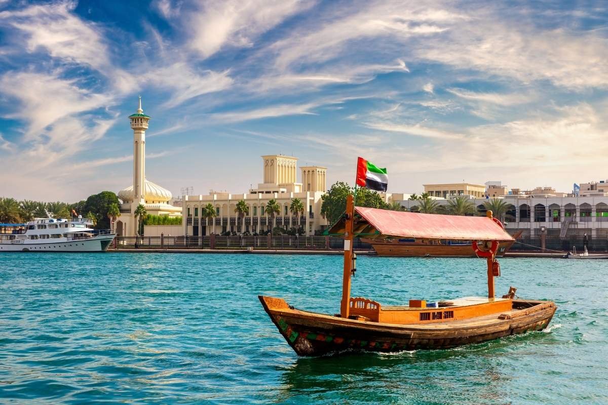 A traditional Abra boat crossing the Dubai Creek at sunset.